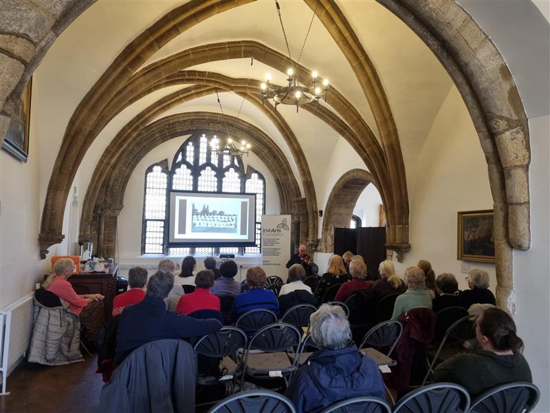 A group of adults sat on chairs watching a presenation