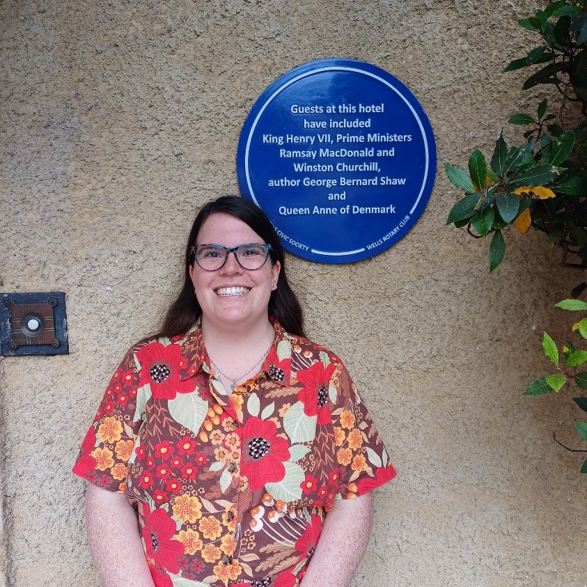 A woman stood next to a blue plaque for guests at a hotel