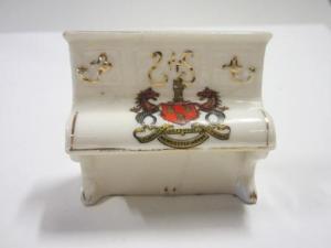 Miniature white porcelain model of an upright piano bearing the crest of Newcastle-Upon-Tyne, Arkinstall & Sons (Stoke-on-Trent) 'Arcadian' crested souvenir ware, early 20th Century. Similar to Goss Crested China