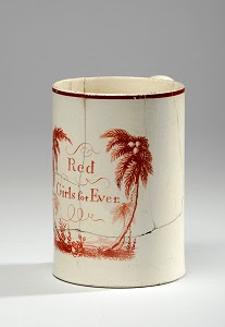 A photograph of a cream jug with red palm trees on and red writing that says Red Girls forever