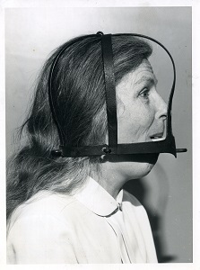 A black and white photograph of a curator wearing the scolds bridle.