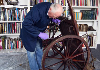 A man cleaning a large wooden cart.