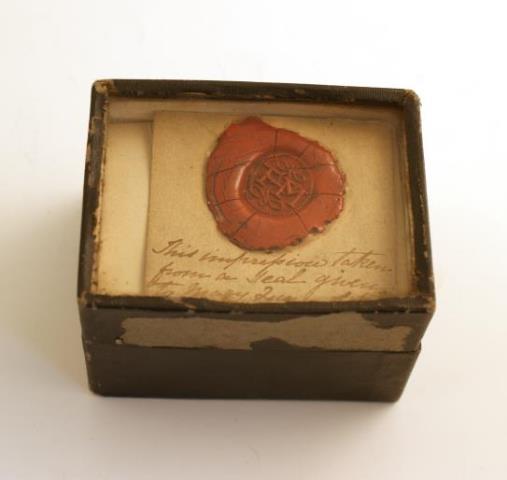 A small box with the wax seal impression of a seal given to Mary by Darnley. The seal is accompanied by a note that says 'This impression taken from a seal given to Mary Queen of Scots by Lord Darnley'