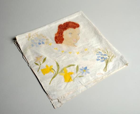 A square handkerchief, painted with daffodils, bluebells and the image of a woman's face, with red hair.