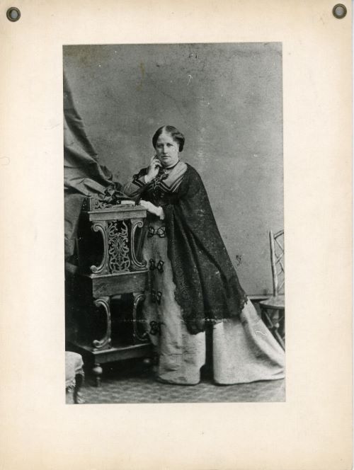 A black and white full length photograph of a Victorian woman posing