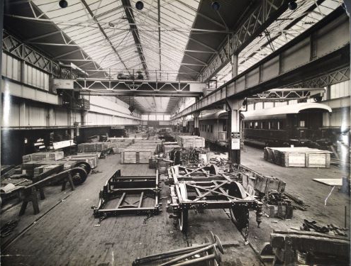 A black and white photograph of a factory floor, with wagons putting together carriages