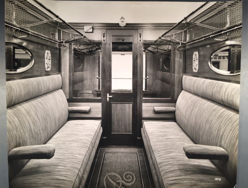 Black and white photograph of a twenties train compartment, with two seats facing each other.