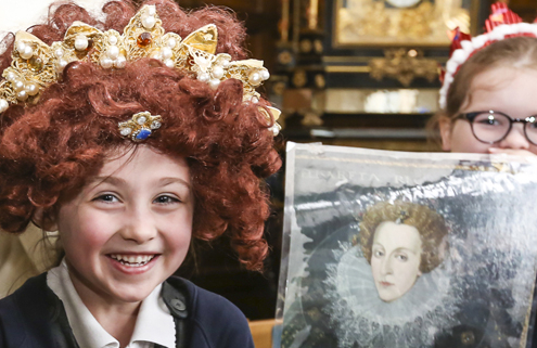 Children having fun in costume and showing off a print of Queen Elizabeth