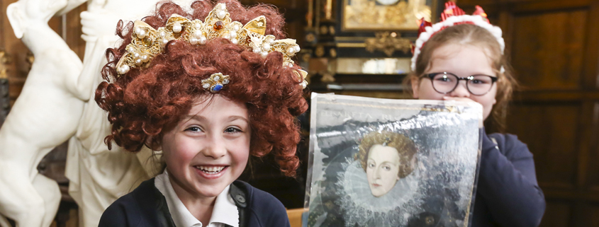 Children having fun in costume and showing off a print of Queen Elizabeth