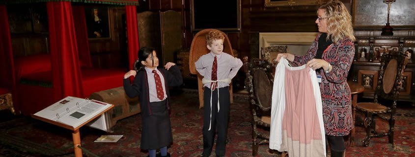 Two children in school uniform are dressing up in period costumes.