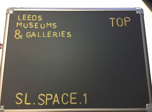 A black box with yellow writing on the front that reads 'Leeds museums and Galleries, Space one'