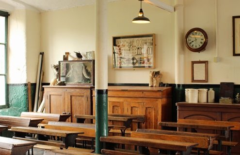 View of a Victorian classroom with wooden desks and traditional furniture