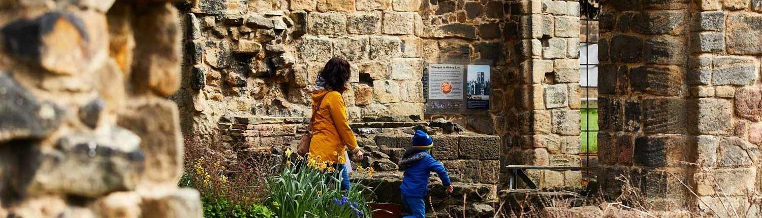 Mother and child walking past Kirkstall Abbey