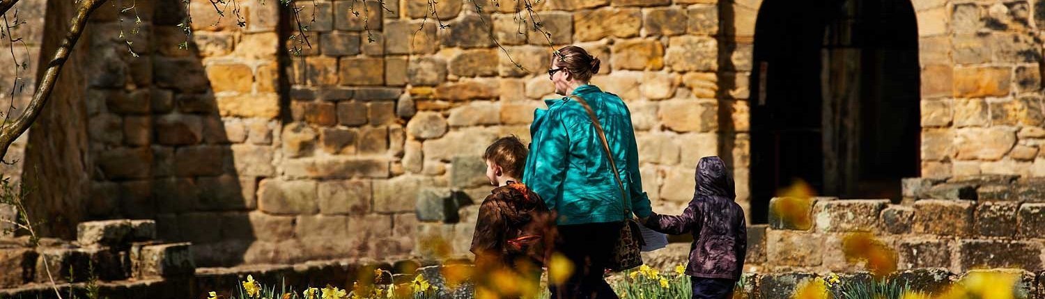 Woman and two children walking past Kirkstall Abbey