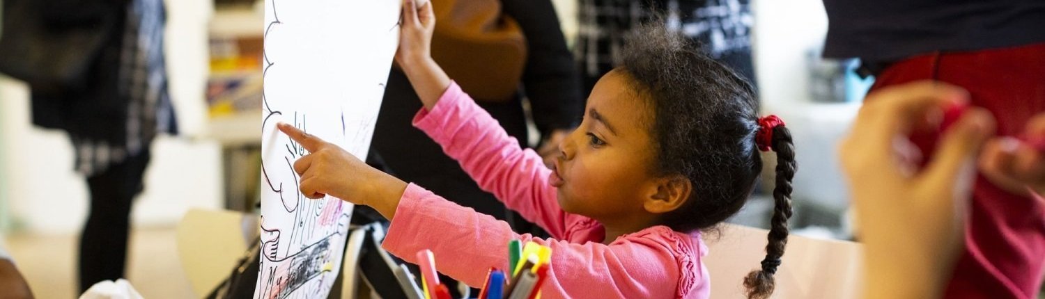 Child pointing at a drawing she is holding up