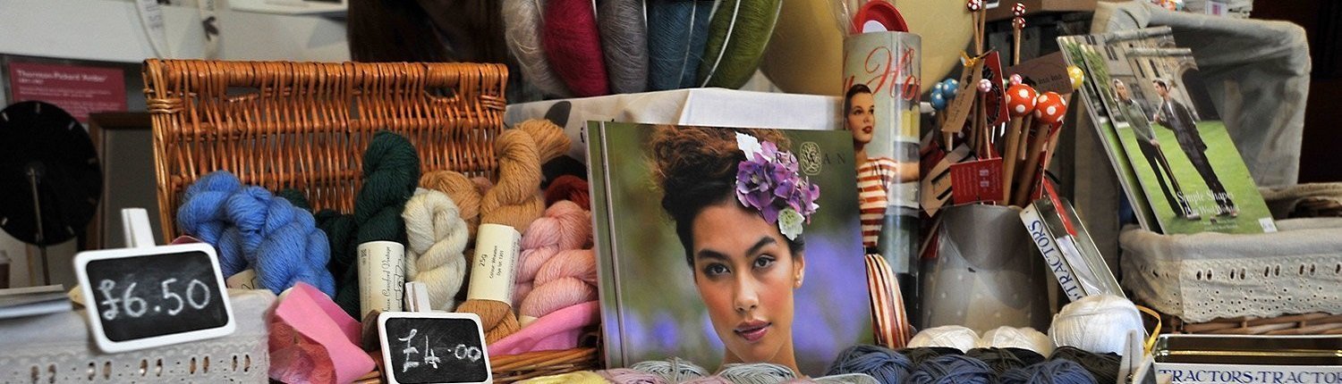 Wool yarns and knots, a book with a woman's face on, magazines, photographs and tins
