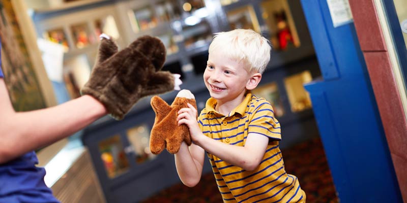 A young boy playing with a fluffy puppet toy at Abbey House Museum