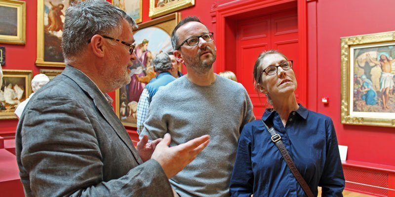 A man is talking to a couple in a gallery