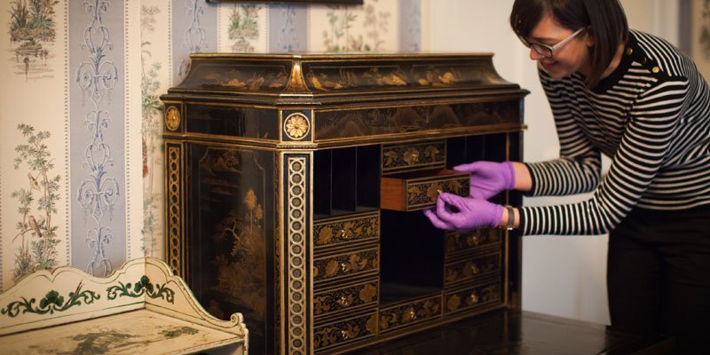 A woman wearing purple gloves is opening a cabinet.