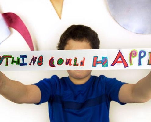A child holing a handwritten banner which reads 'Anything could happen'