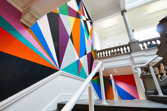 Brightly coloured wall painting by a classic staircase