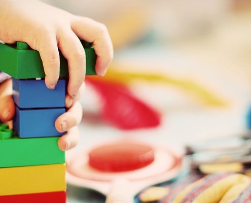 A toddler putting together lego blocks to create a tower