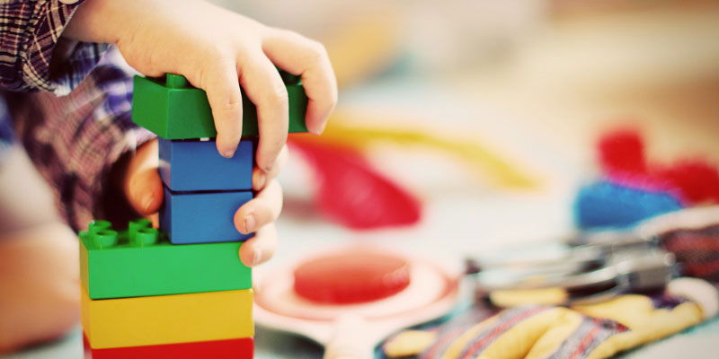 A toddler putting together lego blocks to create a tower