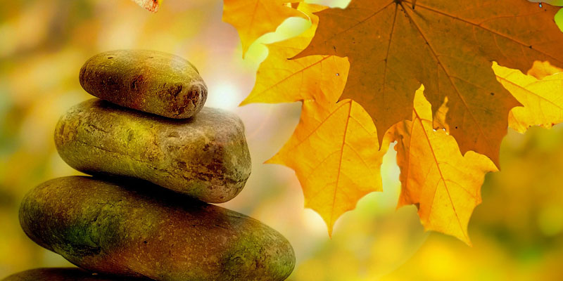Rocks stacked together with an autumnal background