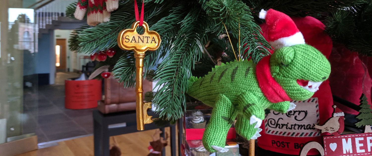 A knitted dinosaur decoration on a Christmas tree at Leeds City Museum shop