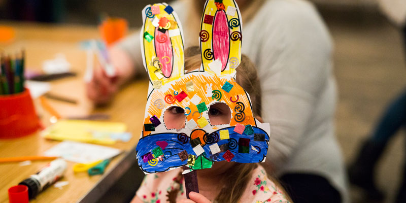 A young girl wearing an easter bunny mask that she has made