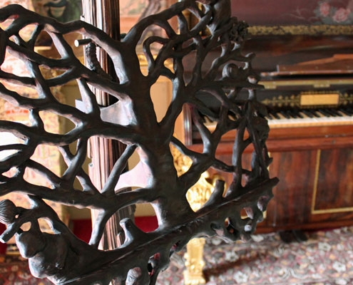 An intricate handcarved dark wood music stand on display in a 16th century music room