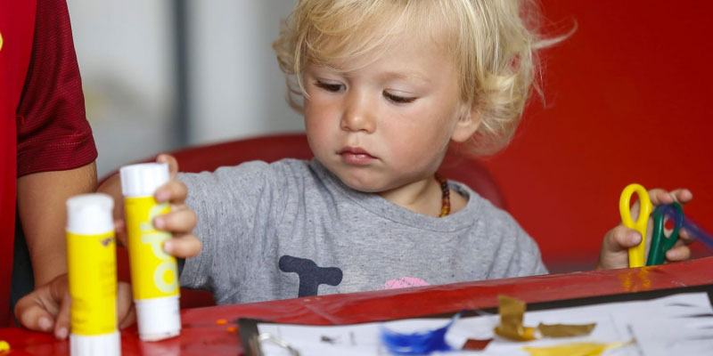 A young boy using a glue stick as part of a craft session