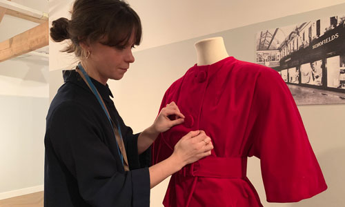 Curator Vanessa Jones adjusts a red suit on a mannequin as part of the Fast x Slow Fashion exhibition at Leeds City Museum
