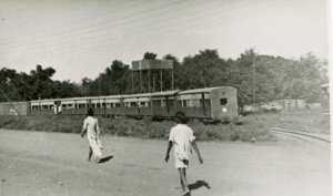 a black and white photograph of two people walking towards a train.