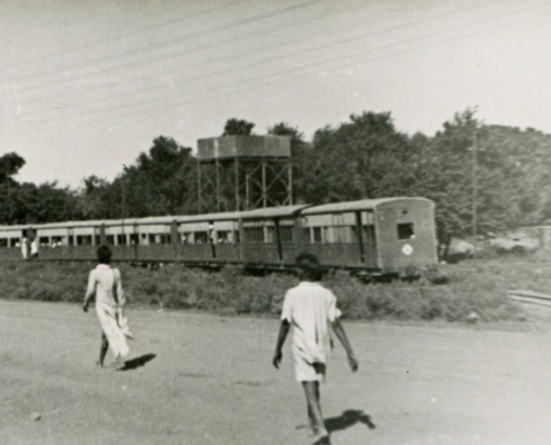 a black and white photograph of two people walking towards a train.