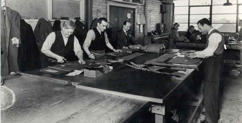 A black and white photograph of Harris Sumrie working in his tailoring business