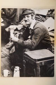 A black and white photograph of a man in a factory having a tea break