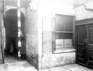 A black and white photograph of the outside of a pub in an alley