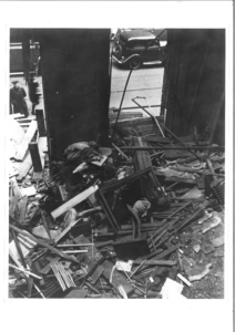 A black and whie photo of a bombed museum, showing debris and objects in a pile on the floor