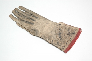 A glove that looks very worn, but has beautiful embroidery on the wrist.