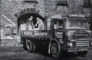 A black and white photograph of men loading putty tins onto a lorry
