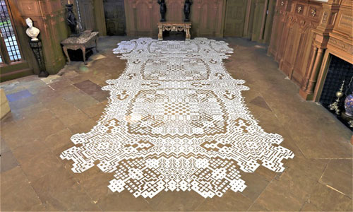 An intricate pattern of salt is laid out on a stone floor of a grand dark 15th century hall