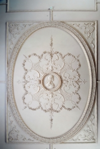 A medallion showing the bust of King George I in plaster on a ceiling.
