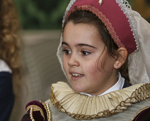 A young girl is dressed in traditional Tudor costume including head wear and a ruff