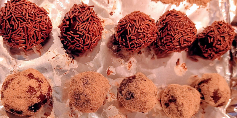 Two rows of chocolate truffles, one covered with chocolate sprinkles, one with cocoa
