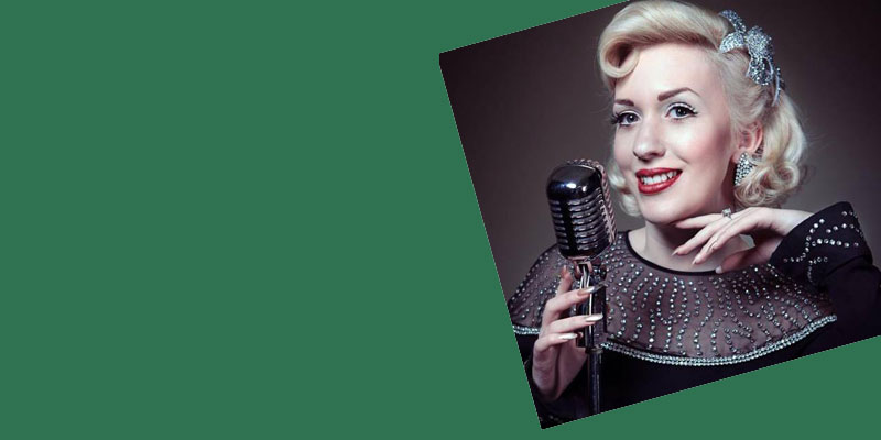 Miss Marina Mae dressed in 1940s clothing with a vintage microphone.
