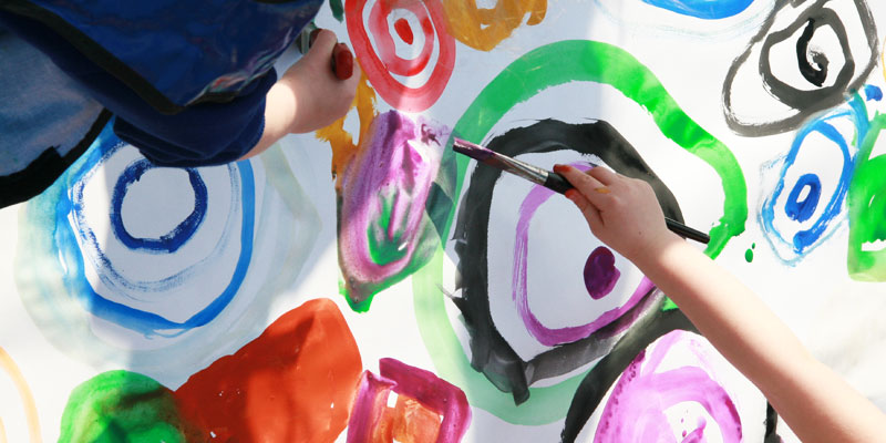 Children painting with bright coloured paint