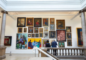 Visitors admire a portrait wall of paintings in Leeds Art Gallery