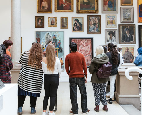 A group of young adults look at portrait paintings in Leeds Art Gallery