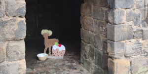 A wooden reindeer dressed in a cooks hat with a mixing bowl and a large christmas pudding at Kirkstall Abbey